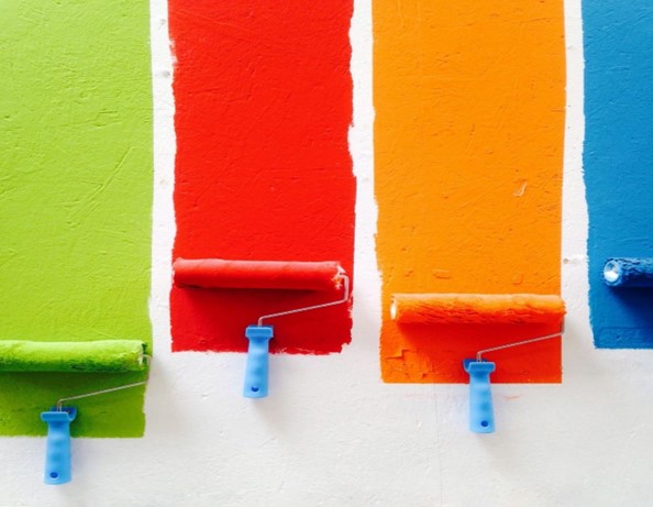 Multicolored painted wall with paint rollers.