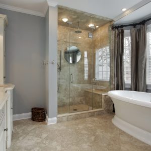 Master bat in luxury home with glass shower and grey painted walls.